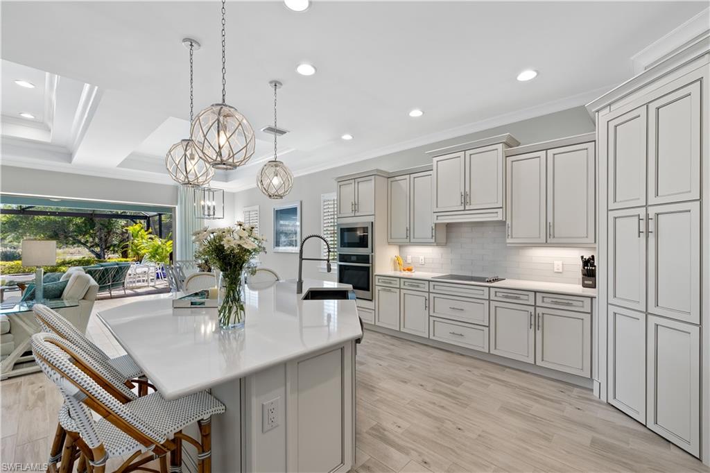 6359 Antigua Way Naples, FL 34113 - Photo 9 of 48 a kitchen with stainless steel appliances granite countertop a sink a stove and chairs