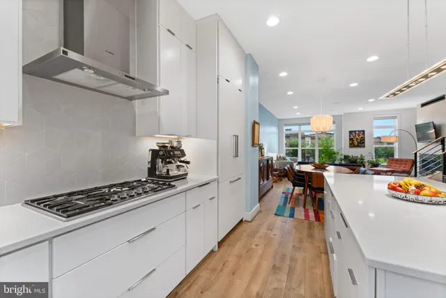 a kitchen with stainless steel appliances a stove a sink a refrigerator and chairs
