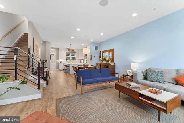 a living room with furniture and a dining table with wooden floor