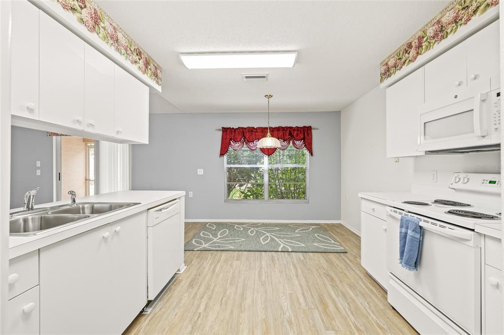 7343 Willowbrook Drive Spring Hill, FL 34606 - Photo 19 of 47 a kitchen with a sink stove and white cabinets with wooden floor