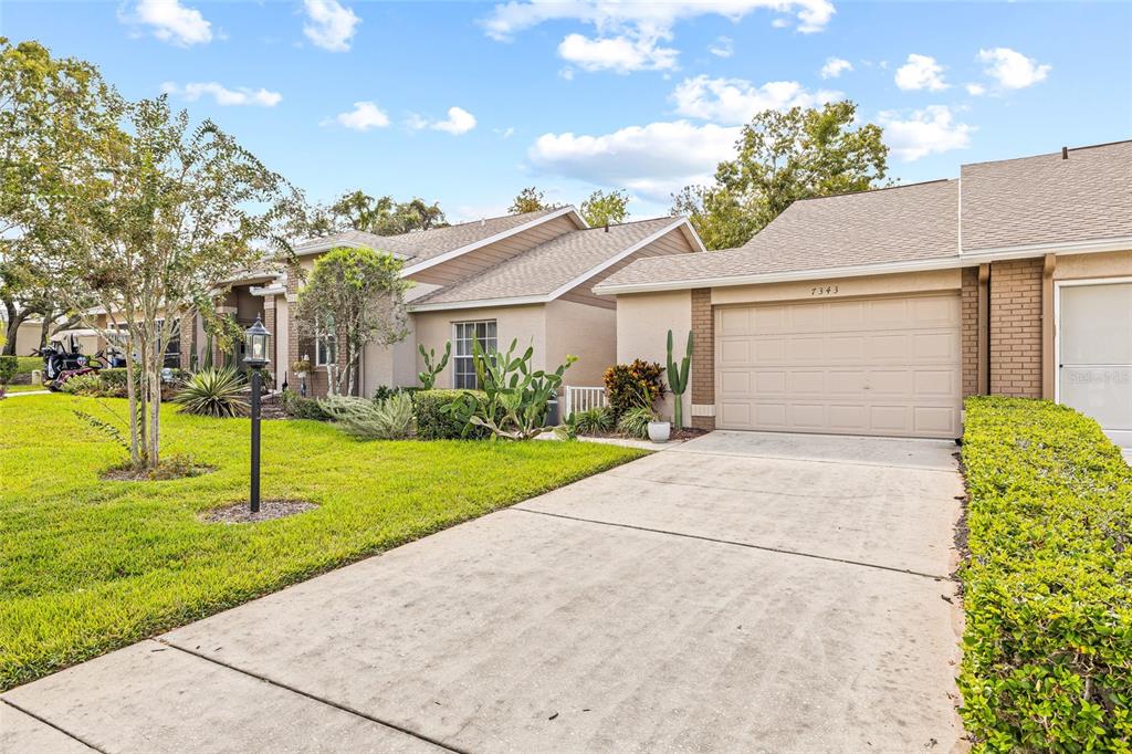 7343 Willowbrook Drive Spring Hill, FL 34606 - Photo 29 of 47 a view of a white house with a yard and potted plants