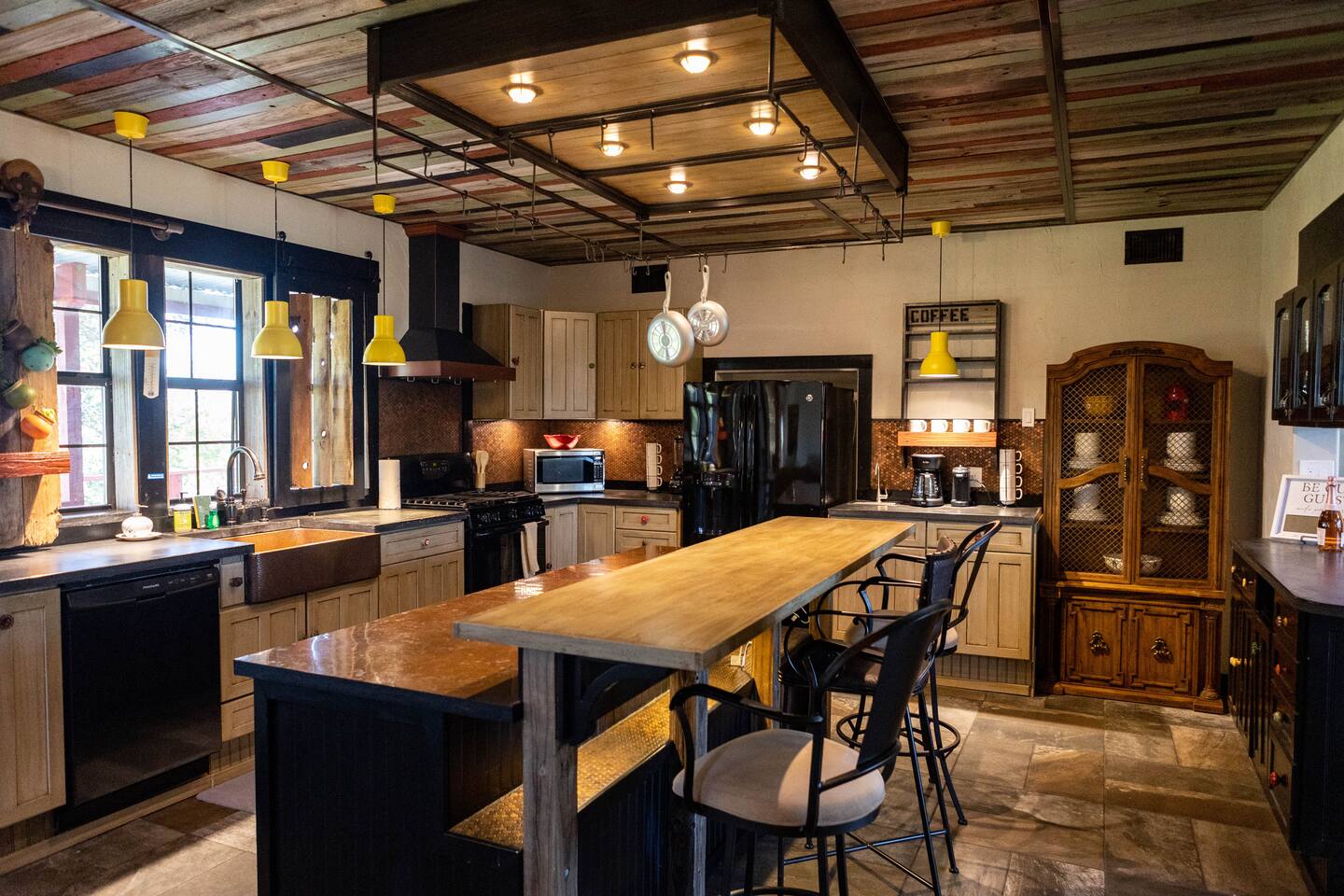 1901 Harmon Hills Road Dripping Springs, TX 78620 - Photo 2 of 27 Kitchen featuring pendant lighting, black appliances, wood counters, dark stone finish flooring, and dark cabinets