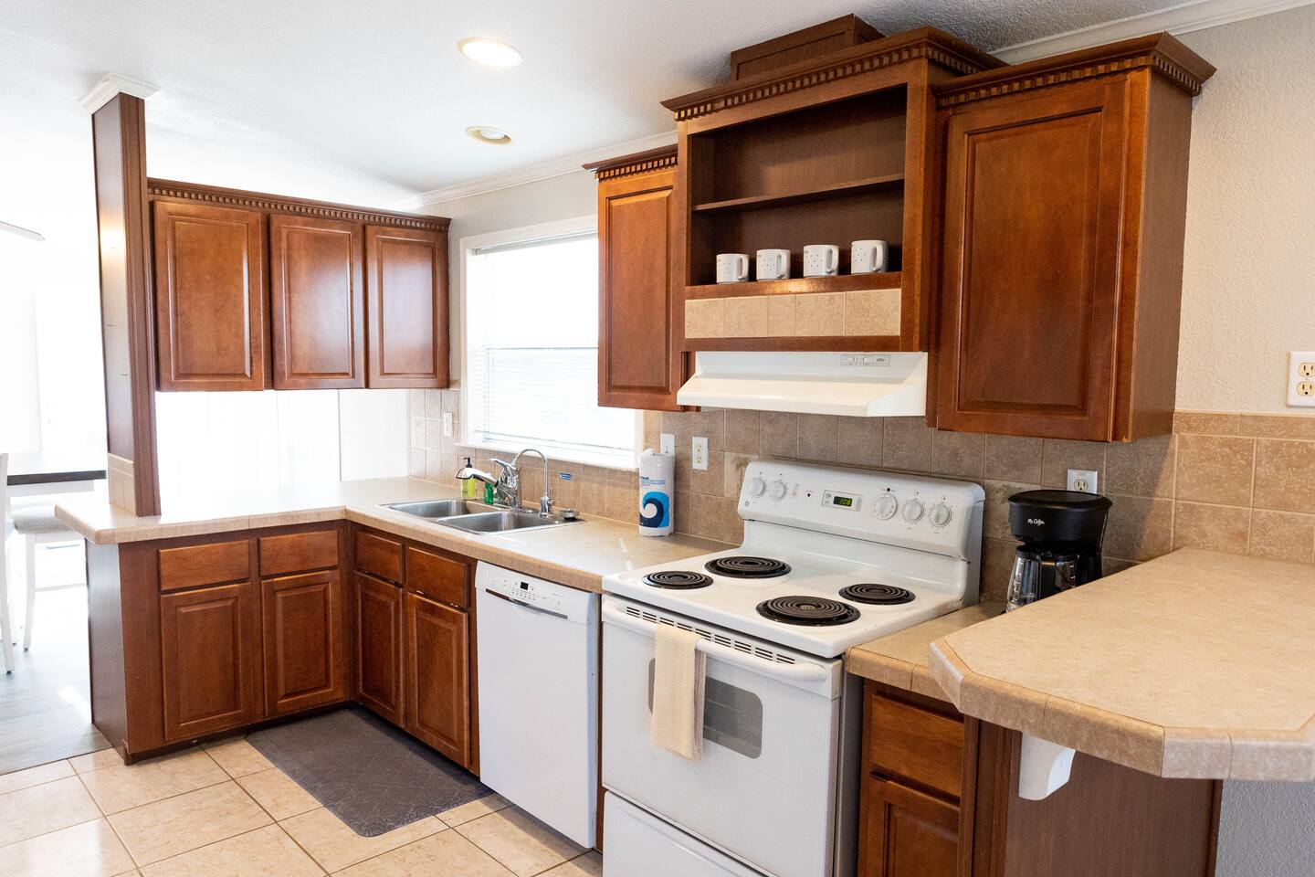 1901 Harmon Hills Road Dripping Springs, TX 78620 - Photo 22 of 27 Kitchen with white appliances, a peninsula, light countertops, open shelves, and wood finish cabinetry