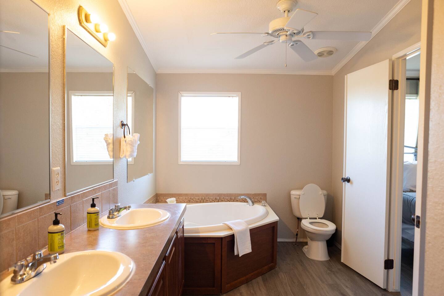 1901 Harmon Hills Road Dripping Springs, TX 78620 - Photo 27 of 27 Full bathroom featuring double vanity, a bath, dark wood-style floors, crown molding, and a ceiling fan