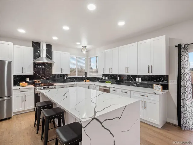 a large white kitchen with a large window and stainless steel appliances