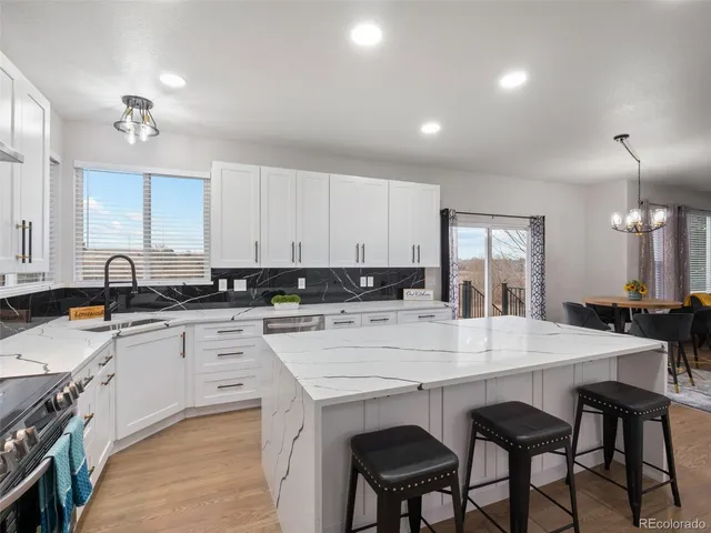 a large white kitchen with a white cabinets and chandelier