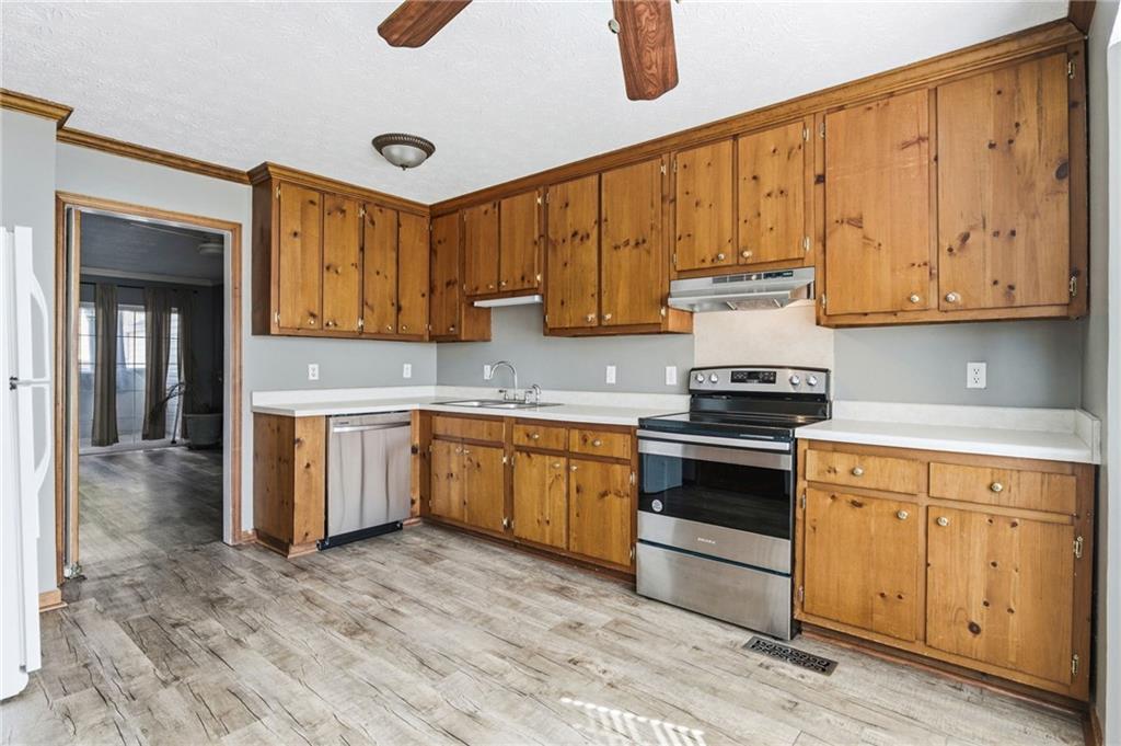 805 Manning Way Southwest Marietta, GA 30064 - Photo 11 of 27 a kitchen with granite countertop a stove a sink dishwasher and white cabinets with wooden floor