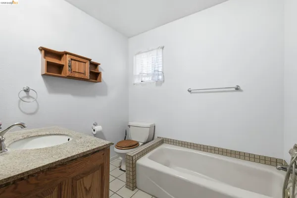 a bathroom with a granite countertop sink and a bathtub