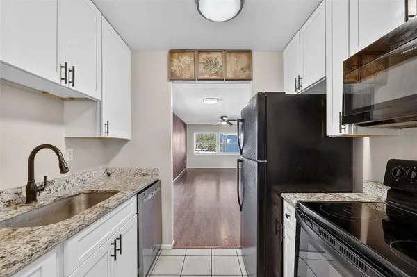 a kitchen with granite countertop a refrigerator stove and sink