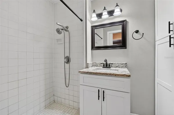 a bathroom with a granite countertop sink a mirror and shower