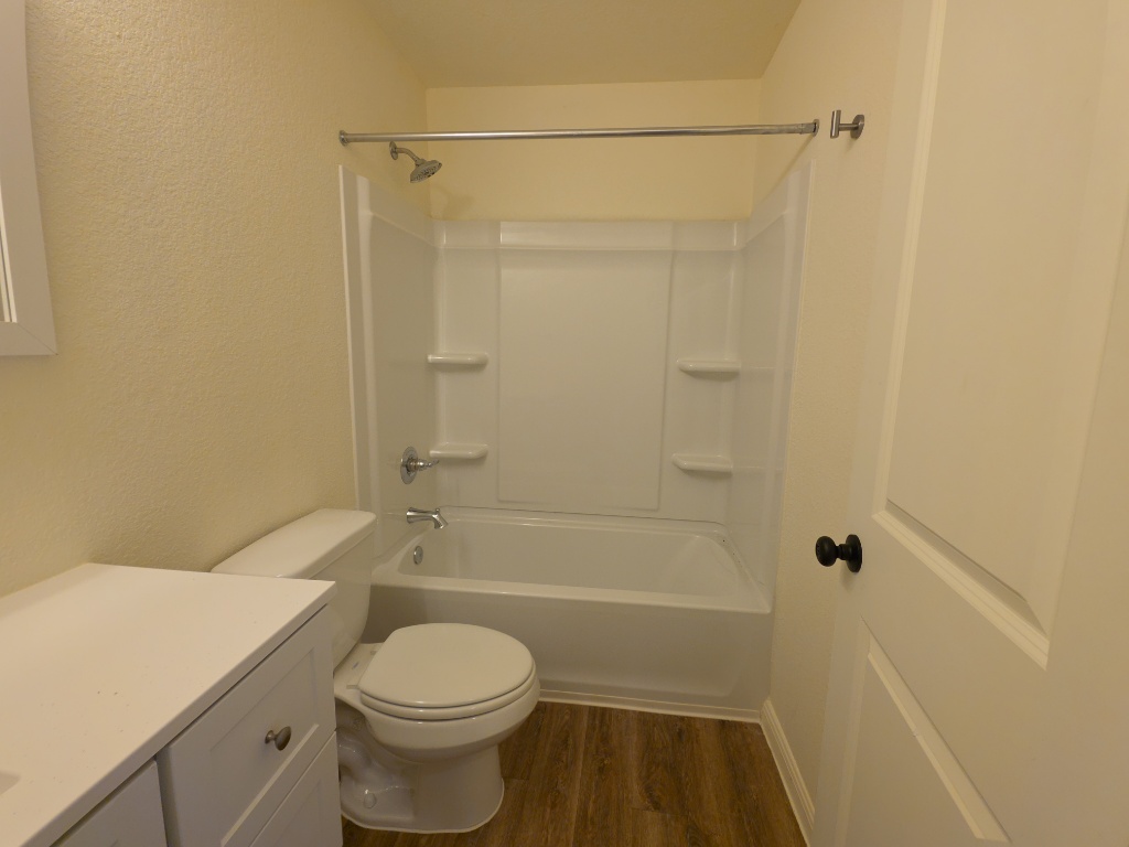 2002 West 2nd Street, Unit 100 Taylor, TX 76574 - Photo 12 of 16 Bathroom featuring vanity, a textured wall, dark wood finished floors, and shower / tub combination