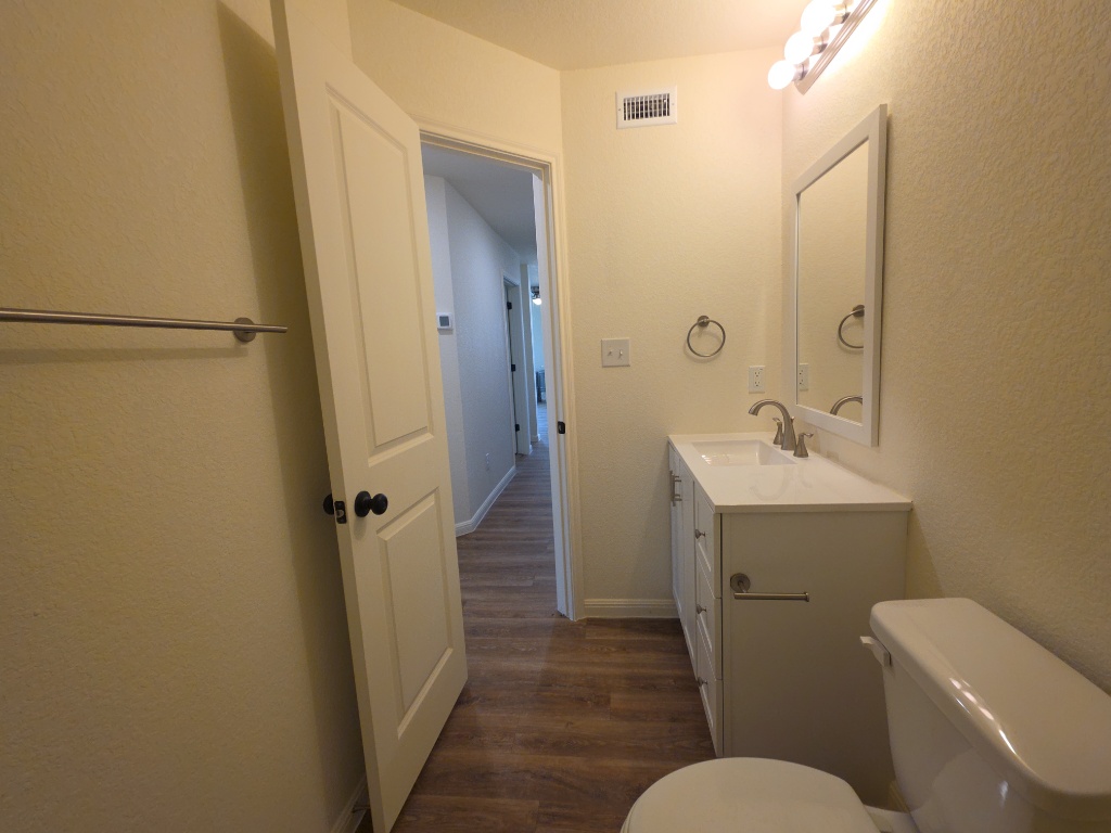 2002 West 2nd Street, Unit 100 Taylor, TX 76574 - Photo 13 of 16 Bathroom with vanity, a textured wall, and dark wood-style flooring