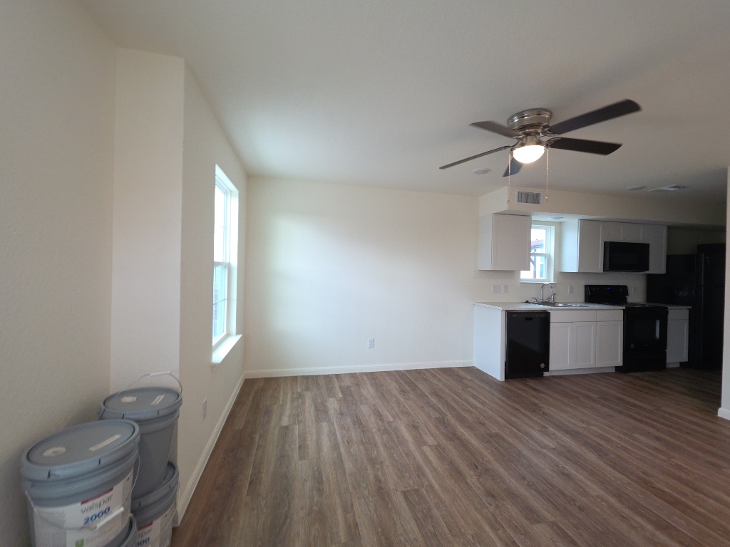 2002 West 2nd Street, Unit 100 Taylor, TX 76574 - Photo 6 of 16 Kitchen with black appliances, light countertops, dark wood-style floors, white cabinetry, and ceiling fan