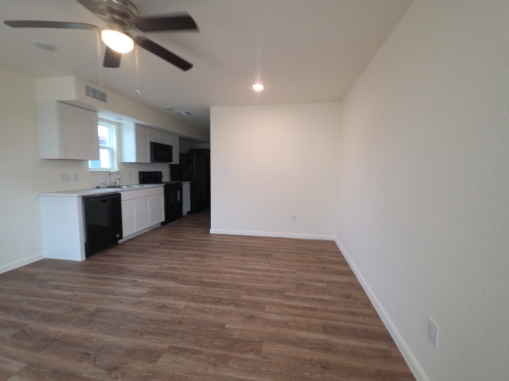 2002 West 2nd Street, Unit 100 Taylor, TX 76574 - Photo 7 of 16 Kitchen featuring light countertops, white cabinetry, electric stove, black dishwasher, and dark wood finished floors