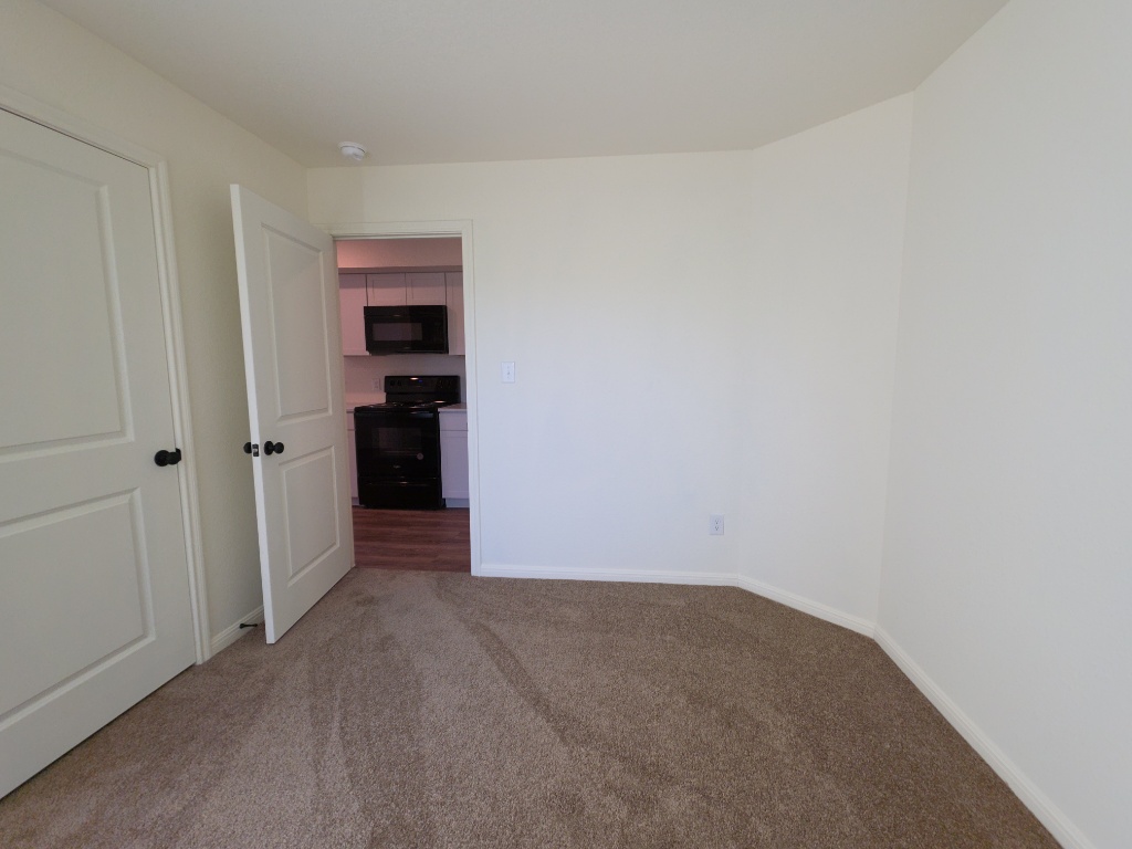2002 West 2nd Street, Unit 100 Taylor, TX 76574 - Photo 9 of 16 Spare room featuring dark colored carpet and baseboards