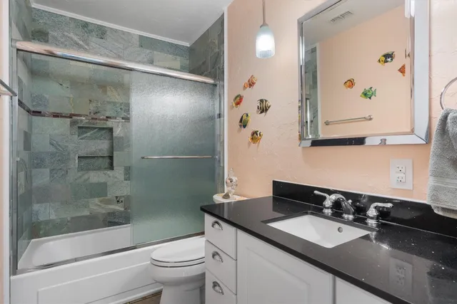 a bathroom with a granite countertop sink toilet and shower