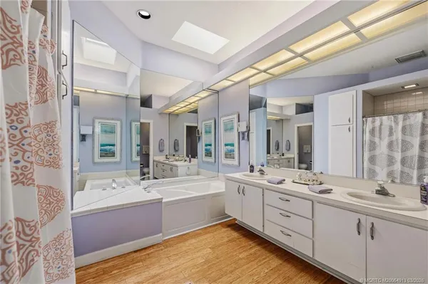 a bathroom with a double vanity sink a mirror and a bathtub