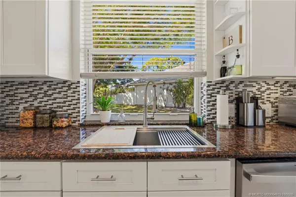 a kitchen with granite countertop a stove a sink and a wooden floor