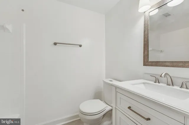 a bathroom with a granite countertop sink a toilet and a mirror