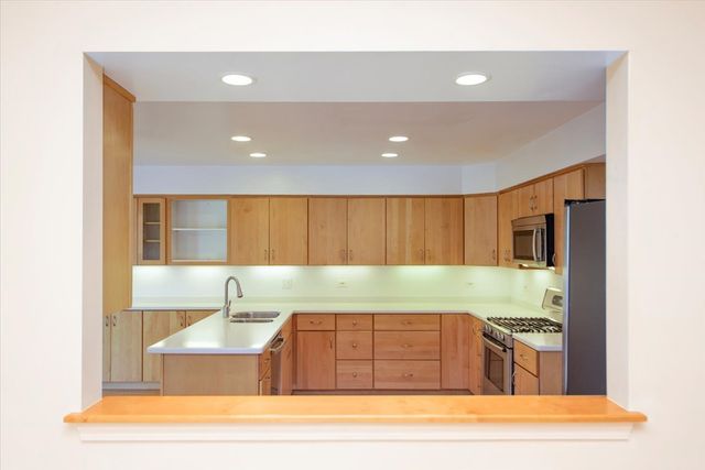 a large kitchen with stainless steel appliances granite countertop a stove a sink and a refrigerator