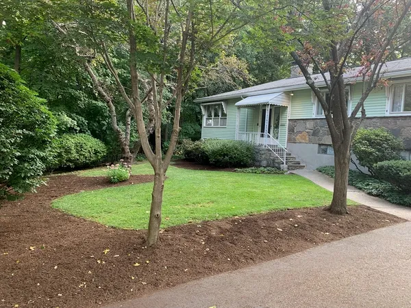 a view of a house with a yard and large trees