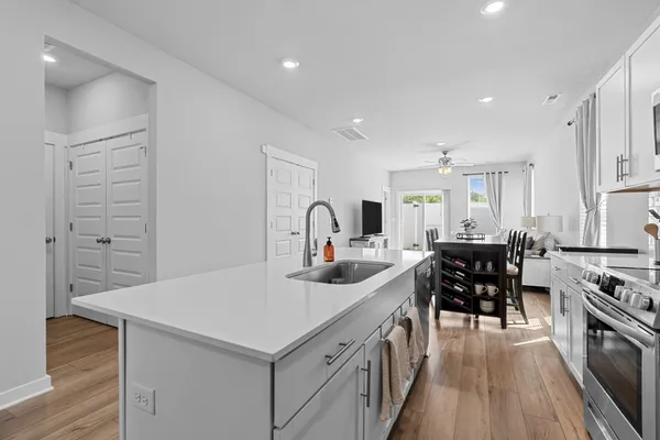 a kitchen with stainless steel appliances a stove oven a sink dishwasher and white cabinets with wooden floor