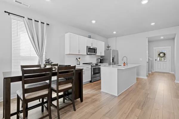 a kitchen with a table chairs a sink dishwasher stove and cabinets with wooden floor