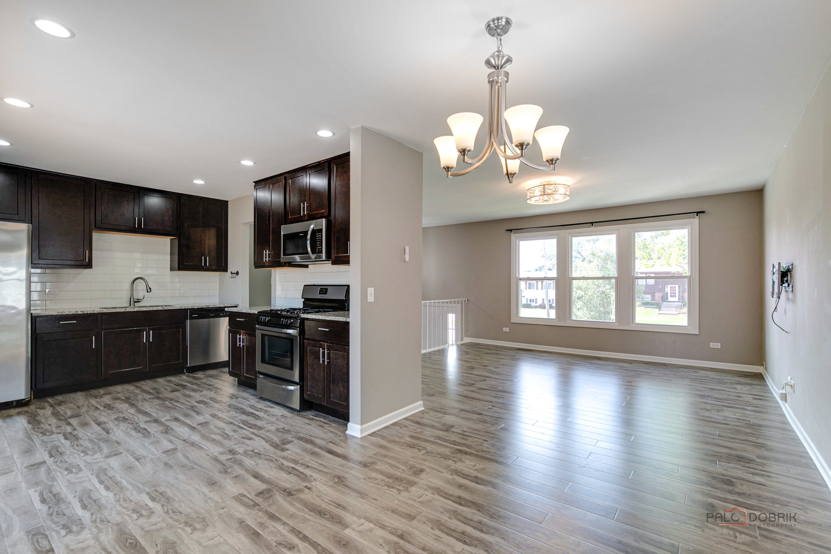 1030 Hassell Road Hoffman Estates, IL 60169 - Photo 6 of 35 a large kitchen with stainless steel appliances granite countertop a stove a sink dishwasher a refrigerator and a fireplace with wooden floor