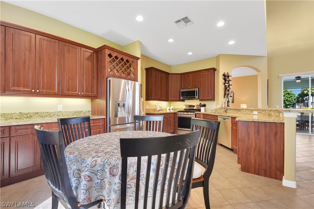 12831 Timber Ridge Drive Fort Myers, FL 33913 - Photo 5 of 16 a kitchen with granite countertop wooden cabinets a dining table and chairs