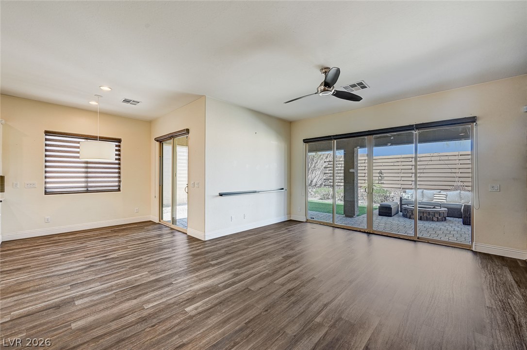 8197 Riley Love Street Las Vegas, NV 89139 - Photo 24 of 48 Rich wood flooring grounds this open living space, offering direct access to a private outdoor patio through sliding glass doors.