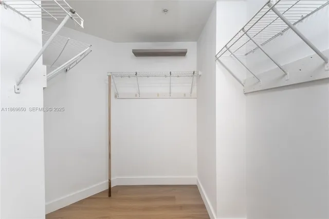 a view of an empty room with wooden floor and closet