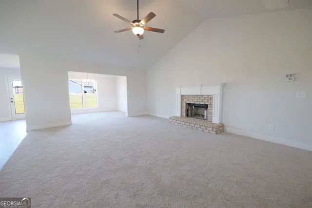 an empty room with a fireplace and a ceiling fan