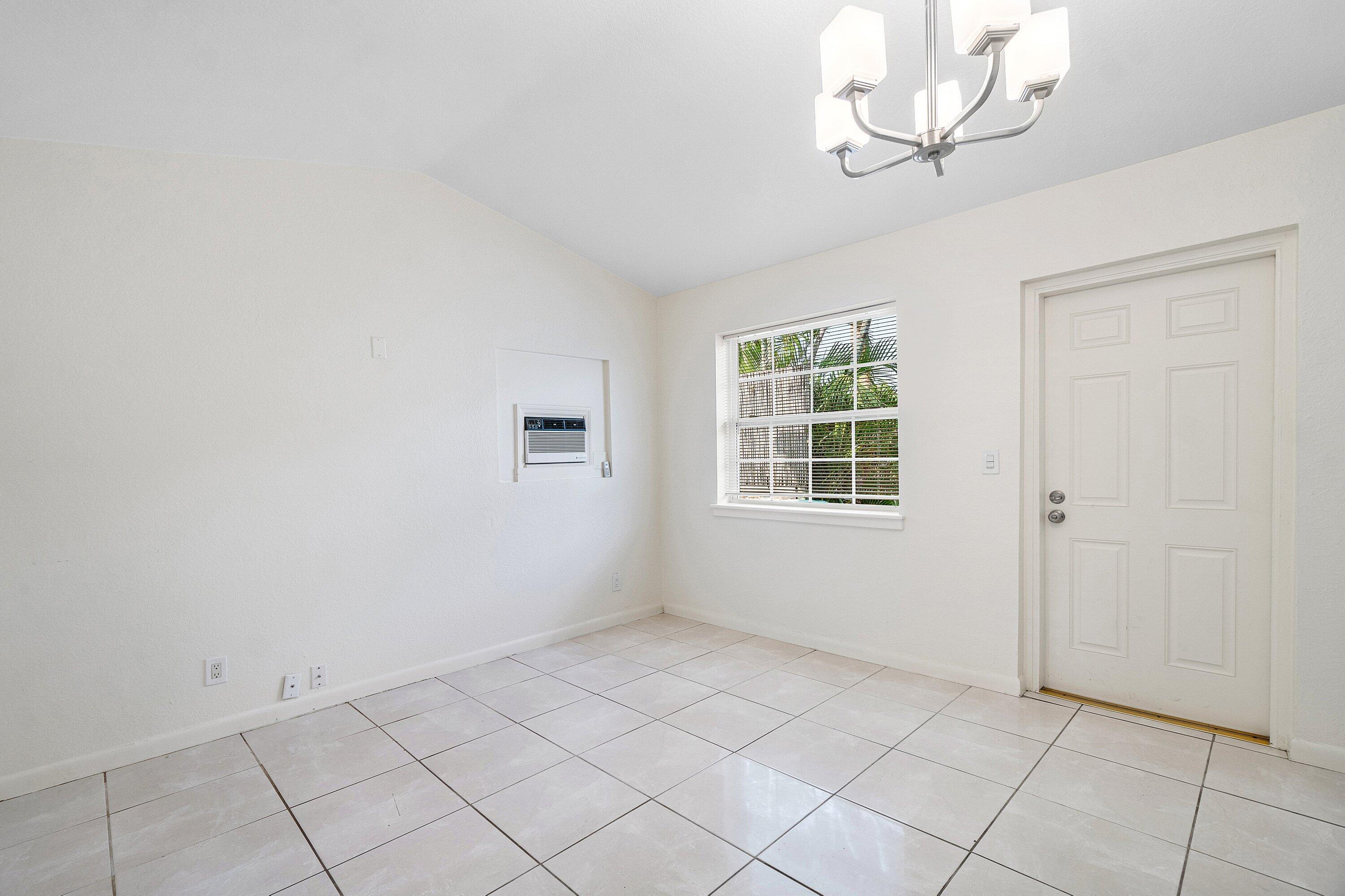 205 Coral Road, Unit 2 Boynton Beach, FL 33435 - Photo 5 of 9 an empty room with a chandelier fan and windows