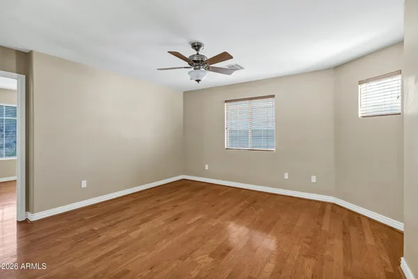 an empty room with wooden floor windows and ceiling fan