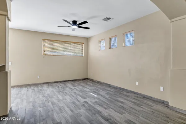 a view of an empty room with wooden floor and a ceiling fan