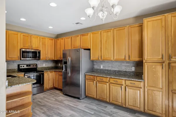 a kitchen with stainless steel appliances granite countertop a refrigerator a stove top oven a sink and dishwasher with wooden floor