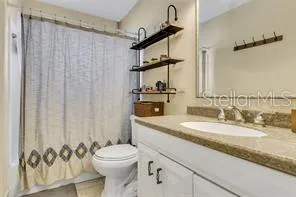 a bathroom with a granite countertop sink toilet and a mirror