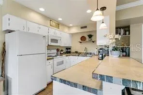 a kitchen with kitchen island a stove a sink a refrigerator and cabinets