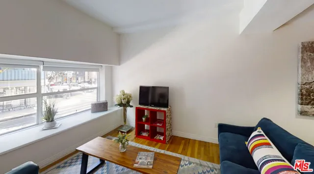 a living room with furniture a flat screen tv and a window