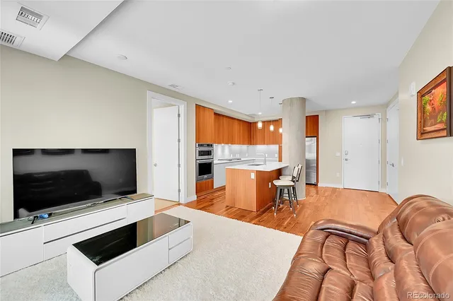 a living room with a flat screen tv and kitchen view