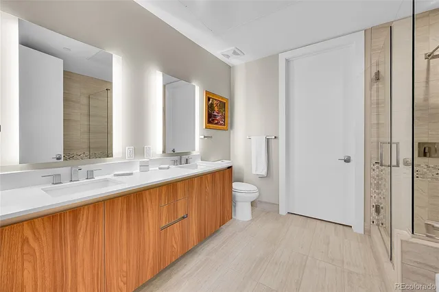 a bathroom with a double vanity sink toilet mirror and shower