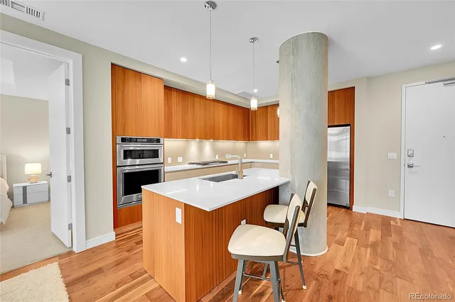a kitchen with stainless steel appliances kitchen island granite countertop a table chairs and a refrigerator