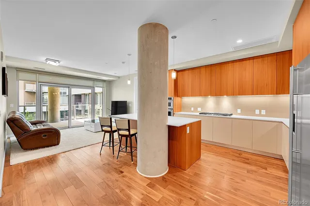 a kitchen with stainless steel appliances granite countertop a refrigerator a sink a stove and island with wooden floor