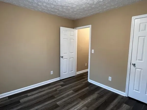 an empty room with wooden floor closet and windows