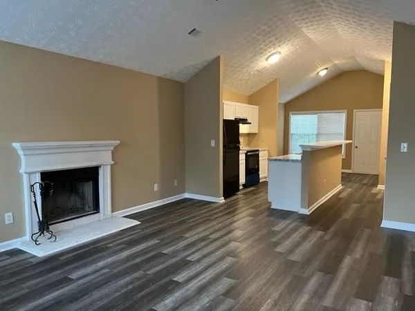 a living room with stainless steel appliances furniture a fireplace and a kitchen view