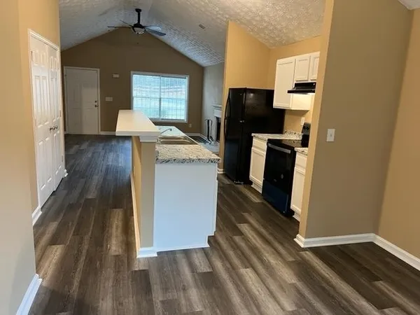 a kitchen with a refrigerator a stove and wooden floor