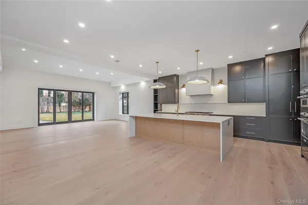 a view of an empty room with kitchen and window