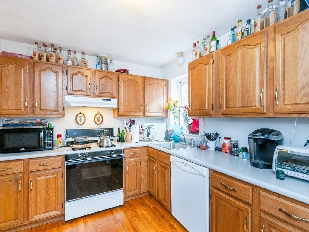 12 Regent Street Cambridge, MA 02140 - Photo 14 of 18 a kitchen with stainless steel appliances granite countertop a sink dishwasher stove and cabinets with wooden floor