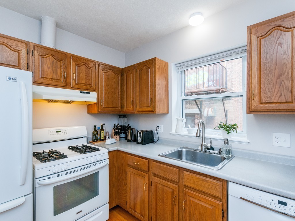 12 Regent Street Cambridge, MA 02140 - Photo 9 of 18 a kitchen with stainless steel appliances a stove a sink a refrigerator cabinets and a window