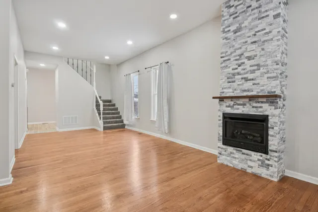 a view of an empty room with wooden floor fireplace and a window